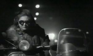 black and white, a woman rides a motorcycle with a side car