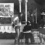 Band rotunda at Albert Park with a sign: "Auckland Women's Centre" with people in front