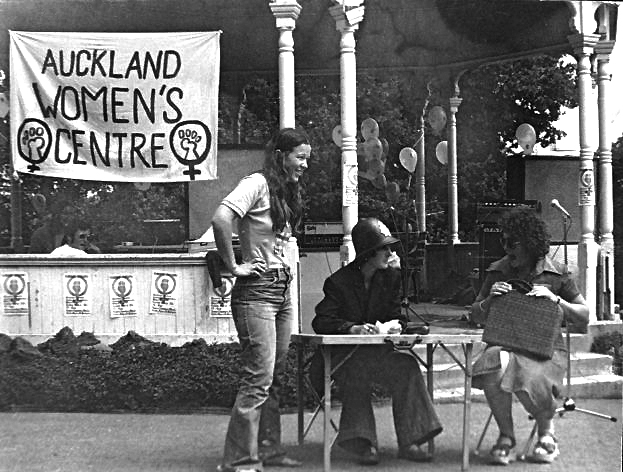 Band rotunda at Albert Park with a sign: "Auckland Women's Centre" with people in front