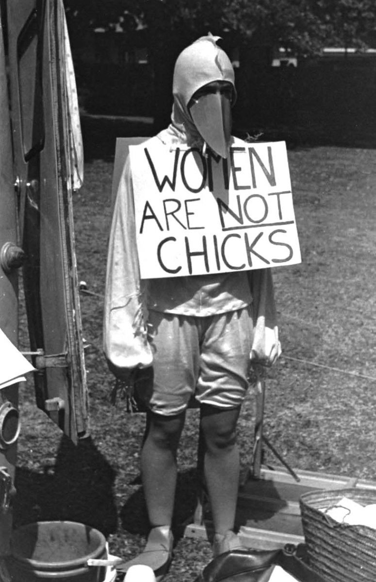 someone wearing a bird costume with a sign: "women are not chicks" black and white image