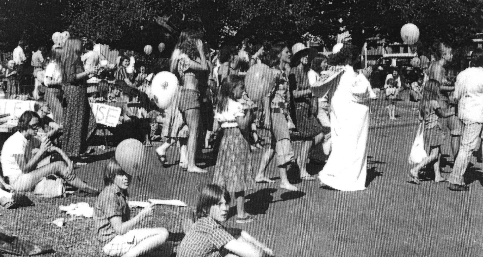 people and balloons in a park, black & white image