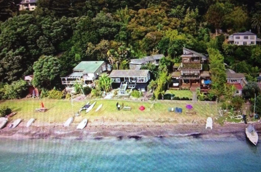 Karaka Bay, showing houses, grass, dinghies on the sand